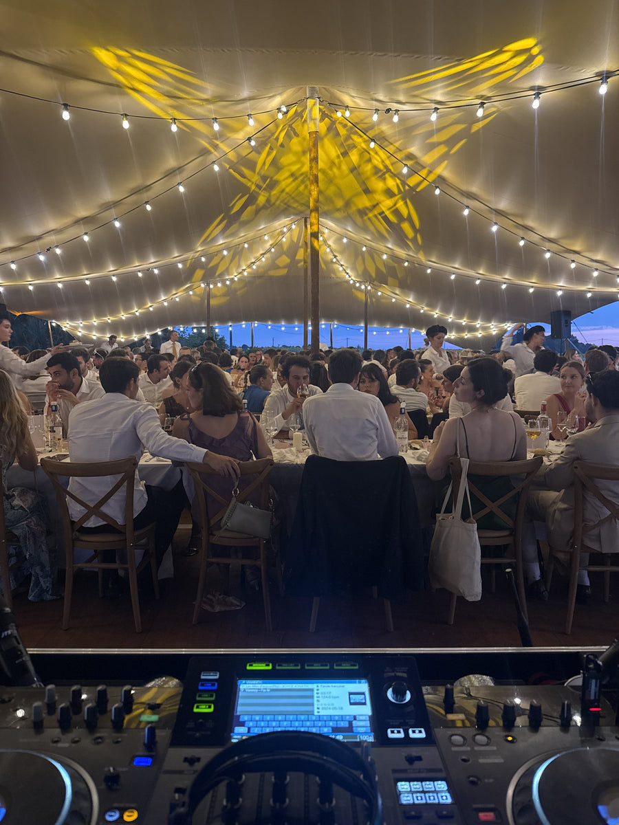 Dîner sous une tente éclairée de guirlandes et de motifs lumineux dorés