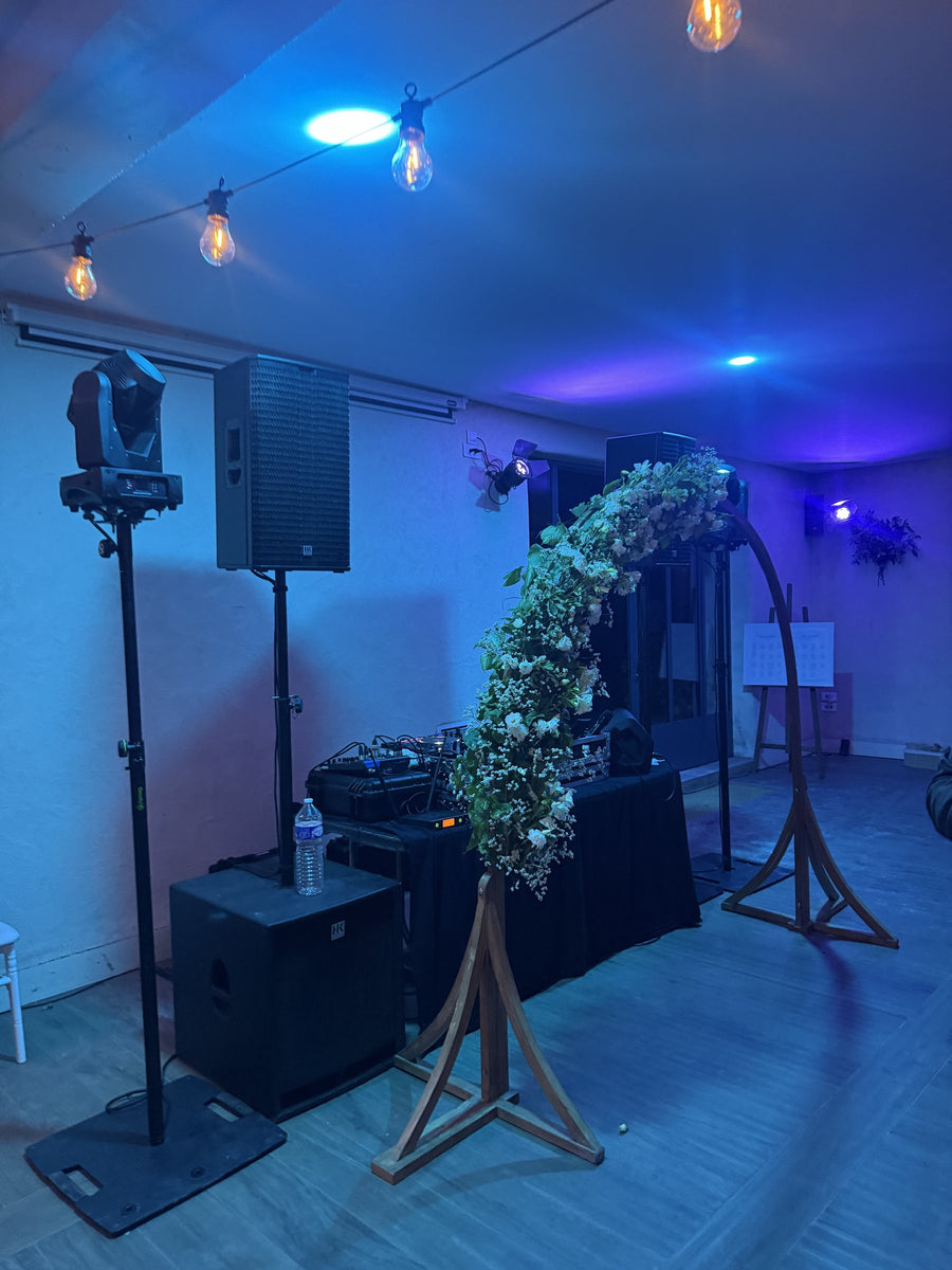 Installation DJ et éclairage à côté d'une arche fleurie