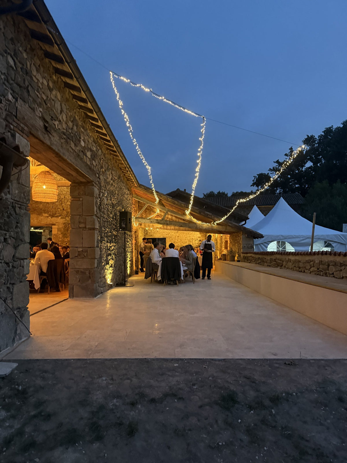 Réception dans une longère en pierre, guirlandes lumineuses à la tombée du jour