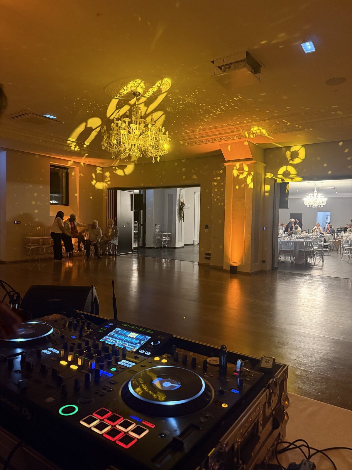 Régie DJ face à une salle de réception éclairée en doré